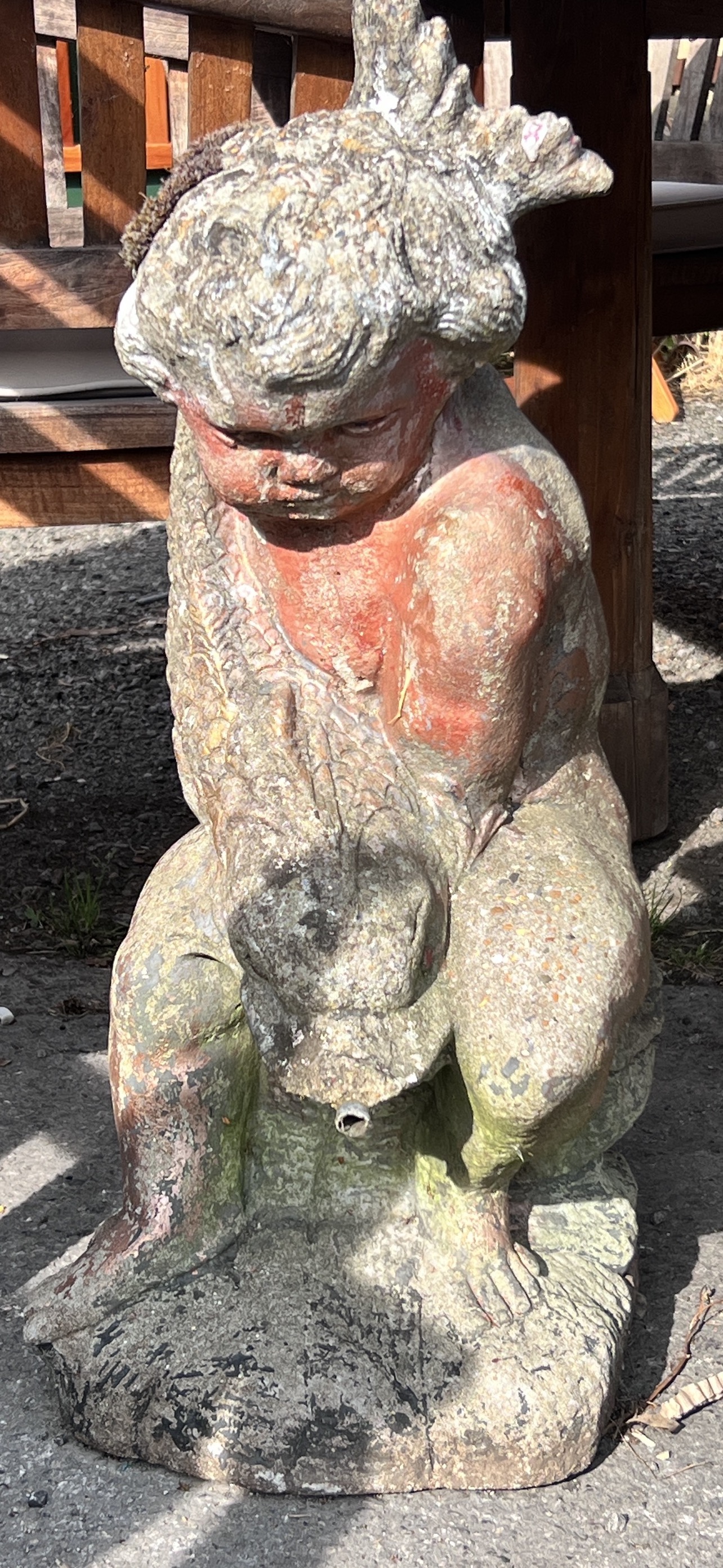 A reconstituted stone garden fountain modelled as a figure of a cherub holding a dolphin, height 69cm